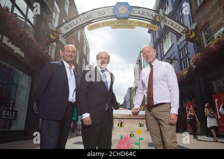 (Von links nach rechts) Simon Quayle, Direktor bei Shaftesbury, Defra Minister für ländliche Angelegenheiten und Biosicherheit Lord Gardiner und Brian Bickell, CEO von Shaftesbury, unter dem Bogen der Carnaby Street, der im Rahmen der Einführung der Defra's Bees' Needs Week vom 9. Bis 15. Juli eine Überarbeitung im Bienenstil erhalten hat. Stockfoto