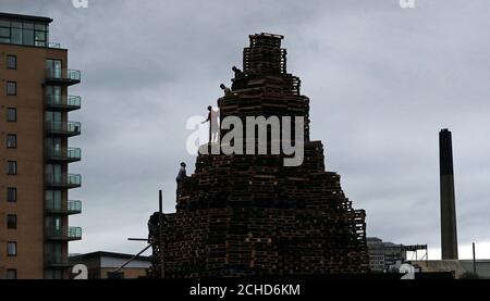 Lagerfeuerbauer in der Sandy Row-Gegend von Belfast, als die Bereitschaftspolizei maskierte Auftragnehmer eskortierte, als sie Holz von zwei umstrittenen loyalistischen Lagerfeuerstellen in Belfast entfernten. Stockfoto