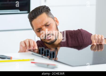 Mann, der das Kochfeld auf die Tischplatte aufgesetzt hat Stockfoto