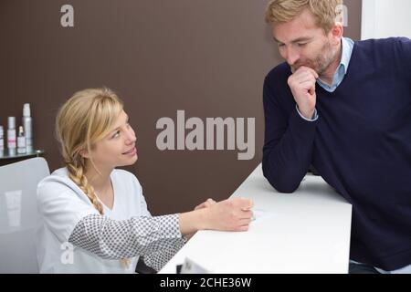 Frau Administrator und den Client auf den Besucher an der Rezeption Stockfoto