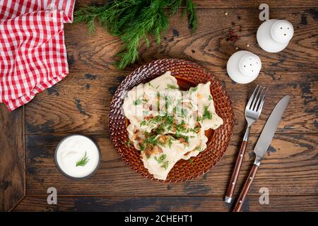 Polnischer Pierogi gefüllt mit Kartoffeln und garniert mit gebratener Zwiebel und Dill auf einem Teller. Gekochte Knödel, varenniki. Nationale Küche Stockfoto