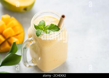 Mango Lassi in einem Glas auf grauen Beton Hintergrund Tisch, kopieren Platz für Text oder Design. Mango Joghurt Smoothie Stockfoto