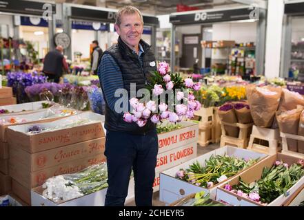 Michael Burgess, ein Händler auf dem New Covent Garden Market in London, bereitet seinen Stand mit saisonalen, hausgewachsenen Blumen für die British Flowers Week vor, die am Montag beginnt. Stockfoto