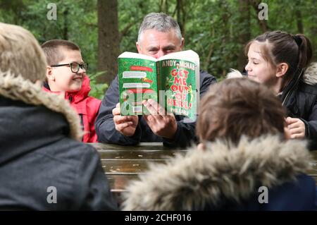 REDAKTIONELLE VERWENDUNG NUR der ehemalige SAS-Soldat Andy McNab liest Sam Gould (links) und Elouise Dobson, beide 9 Jahre alt und aus Slough, zum Launch seines und Autors Phil Earle's neues Buch "Get me out of here!" Bei Go Ape in Slough, Berkshire. Stockfoto