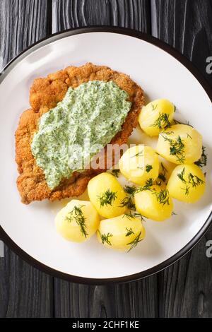 Deutsches Schnitzel mit gekochten Kartoffeln und Frankfurter Grünsauce in Nahaufnahme auf einem Teller auf dem Tisch. Vertikale Draufsicht von oben Stockfoto