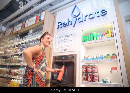 REDAKTIONELLE VERWENDUNG NUR Kunden füllen Wasserflaschen an der kostenlosen Rehydratation Station im Boots Store in Covent Garden, London. Stockfoto