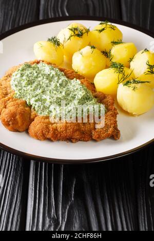 Traditionelle Frankfurter Küche Schnitzel mit gekochten neuen Kartoffeln und grüner Soße aus der Nähe in einem Teller auf dem Tisch. Vertikal Stockfoto