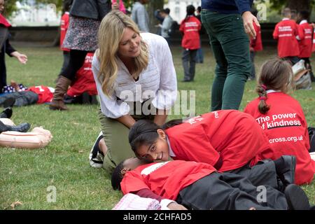 REDAKTIONELLE VERWENDUNG NUR Schulkinder Ayesha Qadeer im Alter von 9 Jahren und Israel Olushola im Alter von 9 Jahren von der Ark Oval Primary Academy School in Süd-London mit der Aktivistin Marina Fogle, die an einem ersten-Hilfe-Skills-Unterricht vor dem Houses of Parliament in London teilnimmt, Nach dem Erfolg einer 10-jährigen Kampagne des Britischen Roten Kreuzes, erste Hilfe in den Schulunterricht in England aufzunehmen. Stockfoto