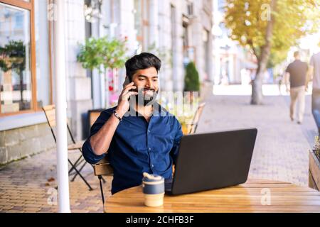 Junger erfolgreicher Geschäftsmann, der im Café im Freien arbeitet. Stockfoto