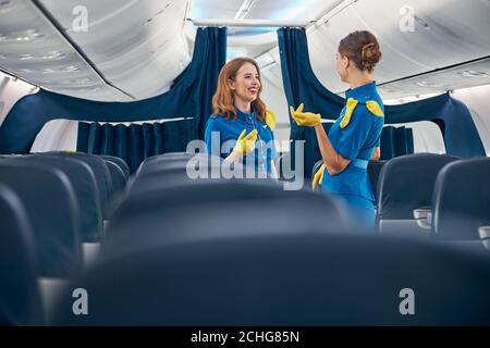 Glücklich hübsche Damen tragen Stewardess Anzug reden zusammen in der Erstklassige Flugzeuge Stockfoto