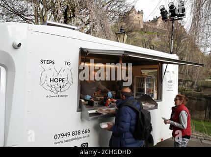 Ritchie Roncero von der Wohltätigkeitsorganisation Step to Hope in Edinburgh gibt Mahlzeiten an Obdachlose in der Pfarrkirche St. Cuthbert in Edinburgh aus. Normalerweise werden Mahlzeiten in der Kirche serviert, aber aufgrund von Einschränkungen werden diese außerhalb an die Obdachlosen übergeben, da das Vereinigte Königreich weiterhin in der Sperre, um die Ausbreitung des Coronavirus einzudämmen. Stockfoto