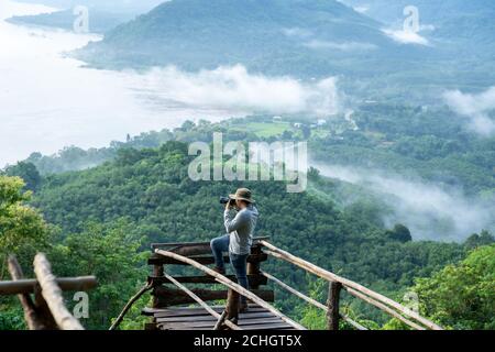 Fotograf Traveller Standing macht ein Foto zwischen Bergen und dem Mekong Fluss bei Phu Huai E -San Nebel Luftbild Landschaft Sang Khom, Non Stockfoto