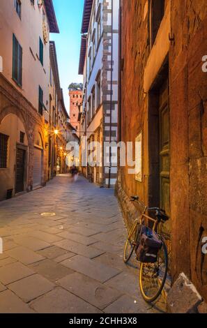 Eine Straße im historischen Teil von Lucca, Italien mit Blick auf den Guinigi-Turm Stockfoto