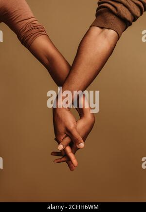 Nebeneinander stehen und die Hand mit verriegelten Fingern halten. Zugeschnittenes Bild von zwei Händen, die Einheit zeigen. Stockfoto