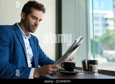 Geschäftsmann sitzt in einem Café und liest eine Zeitung Stockfoto