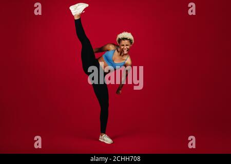 afroamerikanische Fitness-Frau, die auf Flexibilität tut Dehnübungen. Fit Frau dabei Training vor kastanienbraunen Hintergrund. Stockfoto