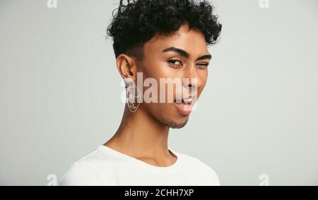 Nahaufnahme eines Mannes mit Augenzwinkern vor der Kamera. Gay Mann vor weißem Hintergrund zwinkend sein Auge beim Blick auf Kamera. Stockfoto