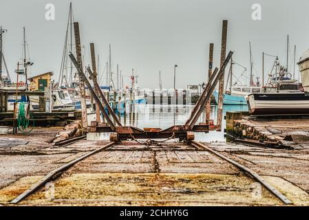 Eine industrielle Eisenbahnrampe oder ein Bootsausleger auf einer Plattform im Hafen von Dragor. Verrostete Schiffseisenbahn oder Slipway auf Gleisen in einem Fischerdorf Hafen Stockfoto