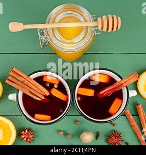 Glühwein in weißen rustikalen Tassen mit Gewürzen und Zitrusfrüchten. Traditionelles Weihnachtsgetränk. Blick von oben. Stockfoto