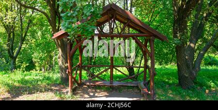 Überdachte Rastplatz in der Nähe eines Waldweges, im Hintergrund Wald. Breites Foto. Stockfoto