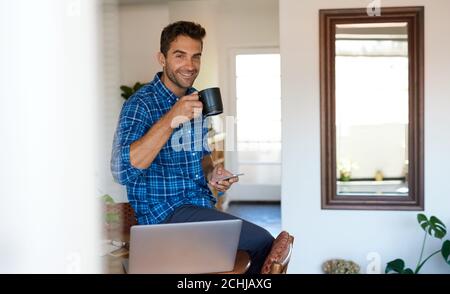 Lächelnder Mann, der eine Pause von der Fernarbeit zu Hause nimmt Stockfoto