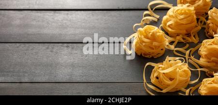 Pasta-Kochkonzept. Rohe Pasta Tagliatelle Nester auf blauem Holztisch Hintergrund, Draufsicht, Kopierraum Stockfoto