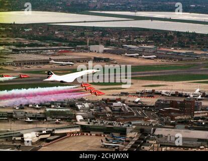 Einen British Airways Concorde führt die Royal Air Force Red Arrows Anzeige Squadron, wie Sie über London Heathrow Flughafen, der feiert sein 50 annniversary war Fliegen. Stockfoto