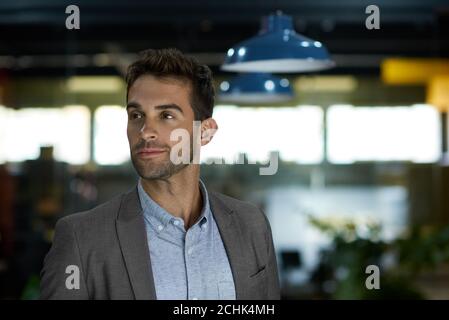 Selbstbewusster Geschäftsmann, der im Büro an die Arbeit denkt Stockfoto