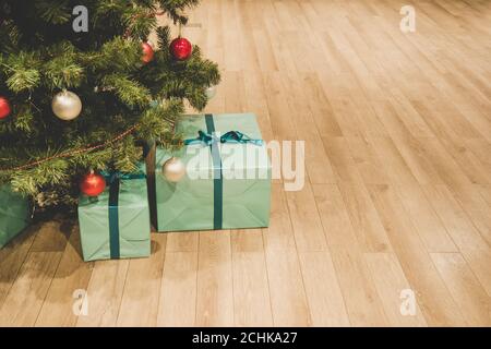 Weihnachtsbaum mit Dekorationen und Geschenke unter ihm innen. Blaue Schachtel auf dem Boden unter dem Weihnachtsbaum. Geschenke vom Weihnachtsmann verpackt in einem Stockfoto