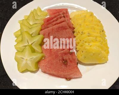 Frische rote Wassermelone, gelbe Ananas und grüne Karambola auf dem weißen Teller zum Essen Stockfoto