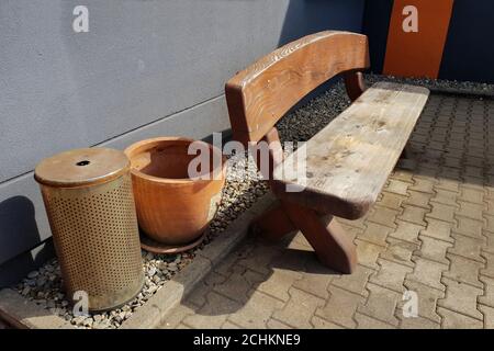Blick auf einen offenen Wartebereich mit langem Holzstuhl Und Mülltonnen auf der Rückseite Stockfoto