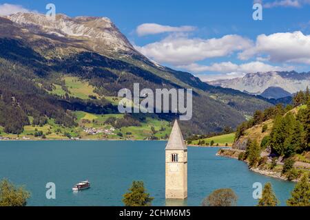 Draufsicht auf eine Kreuzfahrt auf dem Reschensee in der Nähe des alten untergetauchten Glockenturms von Graun Vinschgau, Südtirol, Italien Stockfoto