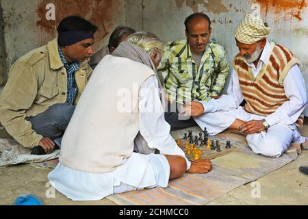 Indische Schachspieler in Mandawa, Rajasthan. Zwei Männer spielen Schach in der Hauptstraße von Mandawa, während drei andere das Spiel beobachten. Stockfoto
