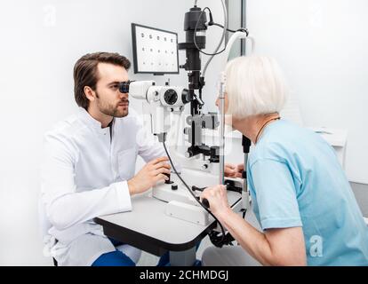 Die Praxis Augenarzt untersucht eine ältere Frau Patienten mit speziellen ophthalmologischen Geräten in einer modernen Klinik. Sehkorrektur bei älteren Menschen Stockfoto