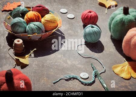 Creative geometric arrangement of craft materials for knitting and crochet on dark table. Yarn balls, crochet hook with thread, decorative felt Stockfoto