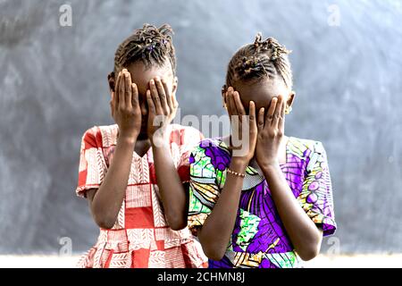 Schöne afrikanische Kinder Mädchen decken Gesichter in Traurigkeit und Verzweiflung Stockfoto