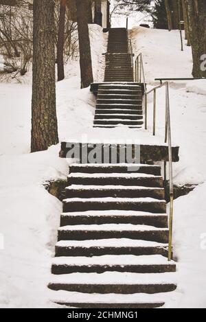 Winter. Treppen. Die Leute gehen auf einer sehr verschneiten Treppe. Unbeputzte, vereiste Treppen vor den Gebäuden, rutschige Treppen Stockfoto