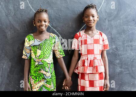 Paar afrikanische Kinder posieren innen in Schule Gebäude Holding Hände Stockfoto