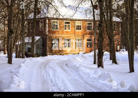Altes verlassene zweistöckiges Haus in ländlicher Umgebung. Die Sonnenstrahlen wärmen die Hauswand. Stockfoto