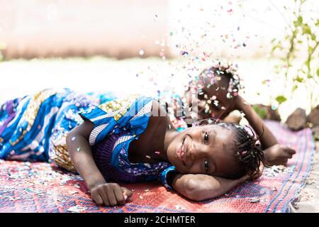 Zwei wunderschöne afrikanische Kinder Mädchen mit Spaß mit Konfetti im Freien