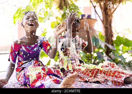 Schöne junge schwarze afrikanische Frauen feiern Neujahr und Christmas Party beim Blasen Konfetti Dekorationen an die Kamera Stockfoto