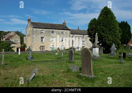 Cottages Beyond the Graveyard of All Saints Church im Dorf Saxton, North Yorkshire, England Stockfoto