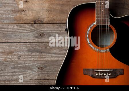 Eine schwarze und orange Akustikgitarre auf Holzboden Stockfoto