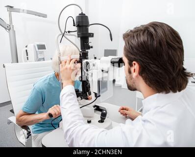 Die Praxis Augenarzt untersucht eine ältere Frau Patienten mit speziellen ophthalmologischen Geräten in einer modernen Klinik. Sehkorrektur bei älteren Menschen Stockfoto