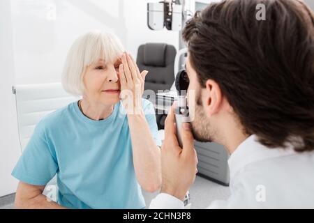 Ältere Patientin, die das Sehen im Optikerbüro überprüft. Augenuntersuchung und Sehdiagnostik Stockfoto