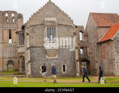 Vier Schutzarbeiter gehen in der Nähe der Ruinen von Castle Acre Priory, einem historischen Cluniac Priorat im Dorf Castle Acre, Norfolk, Großbritannien Stockfoto