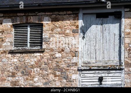 Gebäude Detail: Obere Etage eines alten Lagerhauses am Exeter Quay, zeigt Holz verwittert, Lamellenfenster und Obere Tür. Stockfoto