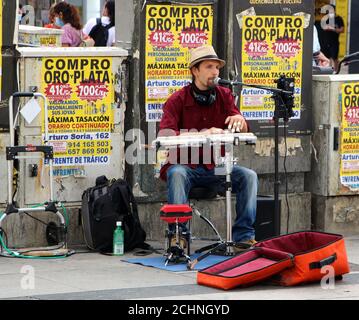 Ein Straßenmusiker spielt ein flaches Saiteninstrument, das in der sitzt Gran Via Madrid Spanien Stockfoto