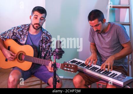 Junge Musiker arbeiten zu Hause mit seiner Videokamera machen Online-Konzert. Arbeiten von zu Hause aus. Musiker. Coronavirus. Stockfoto