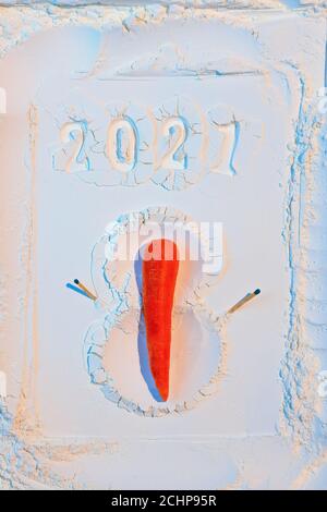 Ein Schneemann aus Mehl mit Karotten und Streichhölzern. Neujahrskonzept Postkarte 2021 Stockfoto
